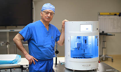 Dr. Munier Nazzal, a UToledo Health vascular surgeon, poses with a 3D graft printer